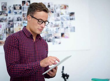 Serious young photographer with tablet computer uploading new photos on social media